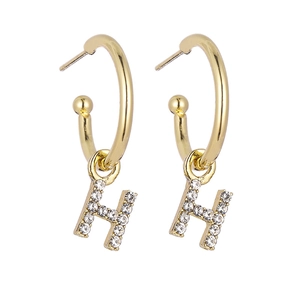 Detailed view of gold earrings with H letter pendants and sparkling micro-pave zircons