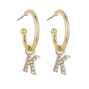 Close-up of golden letter K drop earrings with sparkling crystals on C-shaped hoops