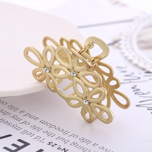 Dettaglio della molletta per capelli a fiore in oro opaco con strass brillanti incastonati