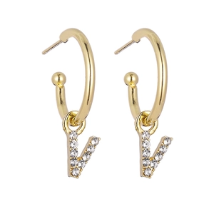 Detail of gold C-shaped hoop earrings featuring rhinestone-studded letter V pendants
