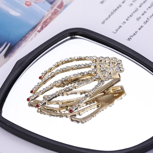 Skeleton hand hair clip in gold metal with sparkling white and red rhinestones