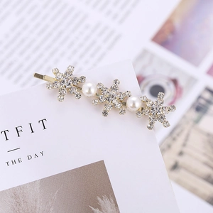 Barrette dorée élégante ornée de strass flocons et perles sur un fond de carte blanc