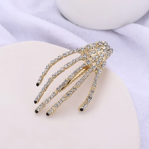 Close-up of golden skeleton hand hair clip with white rhinestones on display tray
