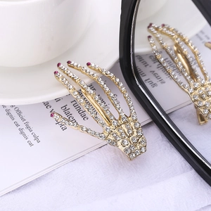 Detailed mirror view of a crystal-studded skull hand hair clip on a book page