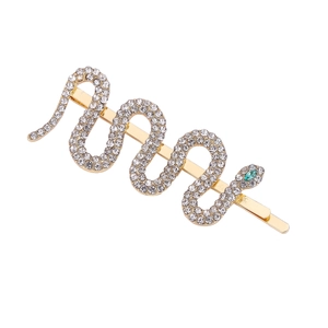 Golden snake hair clip with white rhinestones and green gem eyes on white background