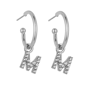 Detail of silver C-hoop earrings with sparkling crystal-studded letter M pendant charm