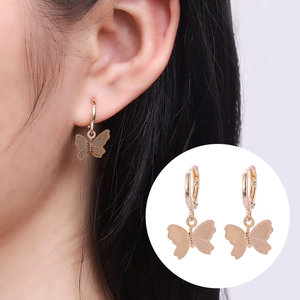 Chic hollow golden butterfly drop earrings with refined engraving on a female model