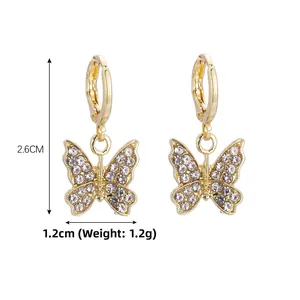 Détail de boucles d'oreilles papillon dorées avec strass brillants et fermoir huggie