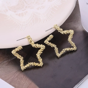 Gros plan de boucles d'oreilles étoiles dorées avec texture martelée et tiges en argent