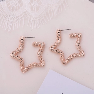 Détail de boucles d'oreilles étoile en or rose avec surface texturée et tiges en argent