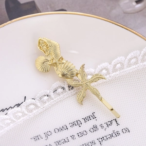 Détail des pinces à cheveux dorées étoile de mer et coquillage avec perle sur dentelle