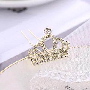 Épingle à cheveux mariée dorée avec couronne en strass sur fond de dentelle blanche