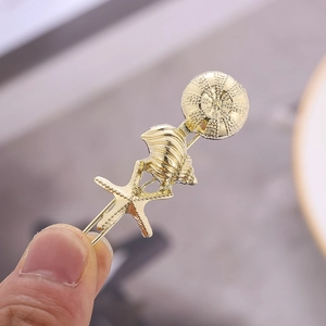 Détails de la barrette marine dorée avec breloques d'étoile de mer et de coquillages fins