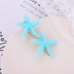 Close-up of blue starfish hair clips with frosted texture on a white decorative tray