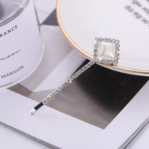 Detailed close-up of a silver hair clip featuring a square pearl and sparkling crystals