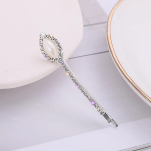 Elegant silver hair clip with pearls and sparkling crystals on a white ceramic plate