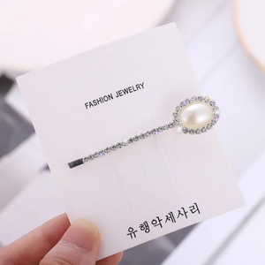 Detailed view of a silver hair clip featuring faux pearls and sparkling rhinestones