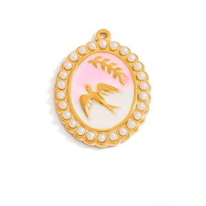 Macro shot of oval gold pendant featuring pearl border and pink floral bird engraving
