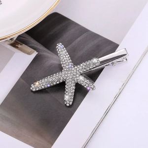 Close-up of a silver starfish hair clip with sparkling blue and purple rhinestones