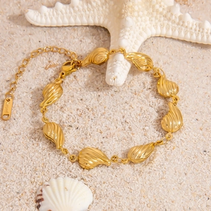Detailed view of the 18K gold plated seashell link bracelet on beach sand with sea stars