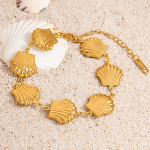 18K gold plated stainless steel bracelet featuring radiant shell charms on a sandy beach background