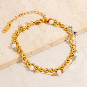Dettaglio di un bracciale in acciaio inossidabile dorato con perline colorate e perle