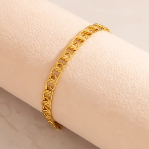 Primo piano di un bracciale a maglia cubana piatta dorata avvolto su un supporto espositivo