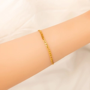 Detailed view of 18K gold-plated wavy Figaro chain bracelet worn on a female wrist