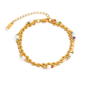 Dettaglio del bracciale a catena a cuore dorato a doppio strato con perle e ciondoli colorati