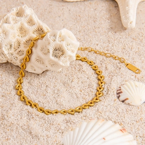Elegante bracciale a maglie a cuore placcato in oro su una spiaggia bianca con conchiglie