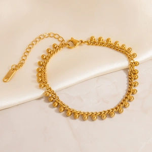 Detailed macro view of 18K gold-plated beaded bracelet with lobster clasp on silk