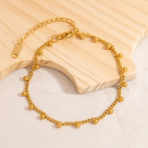 Detailed macro view of 18K gold curb chain with small beads and lobster clasp closure