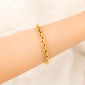 Close-up of minimalist gold-plated interlocking chain bracelet worn on a wrist
