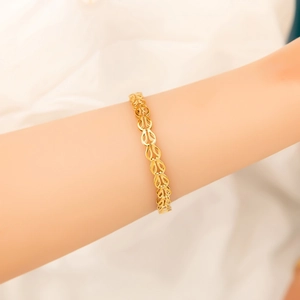 Detailed macro view of an 18K gold-plated stainless steel bracelet on a soft knit fabric