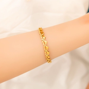 Detailed view of interconnected heart chain bracelet in 18K gold finish on a wrist