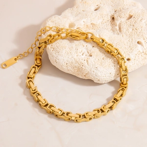 18K gold-plated stainless steel Byzantine chain heart bracelet on a white stone base