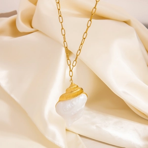 18K gold seashell necklace with a white baroque pearl pendant on cream silk fabric