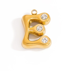 Macro detail of gold-plated 18K letter E pendant with three sparkling crystal zircons