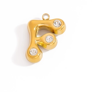 Macro shot of gold stainless steel letter F pendant with three sparkling zircon stones
