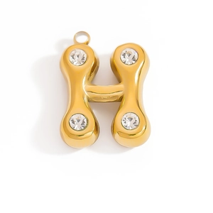 Macro detail of 18K gold H letter charm pendant with clear crystal rhinestones on white background
