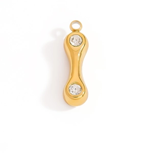 Macro detail of gold-plated dumbbell pendant with inlaid clear zircon stones