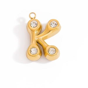 Macro detail of gold-plated letter K pendant with zircon stone inlays on white background