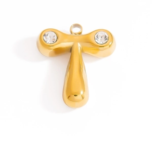 Macro detail of a polished golden T letter pendant inlaid with sparkling white cubic zirconia