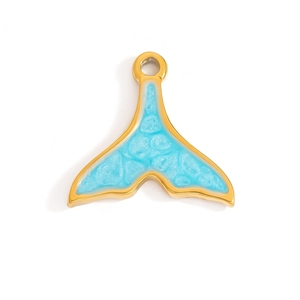 Primer plano de un colgante de cola de ballena dorado con esmalte azul y acabado brillante