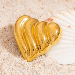 Pendentif cœur en or 18 carats poli avec texture ondulée sur fond de sable blanc