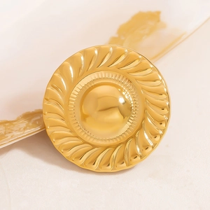 Macro detail of round 18K gold plated brooch with spiral relief texture for luxury coats