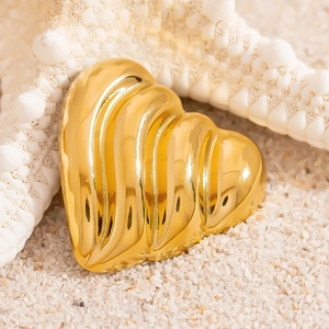 Broche cœur en or 18K avec texture ondulée sur fond de sable et d'étoile de mer