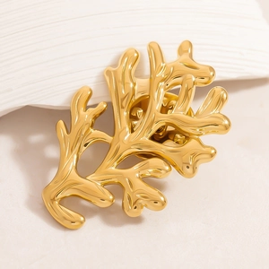 Détail macro d'une broche branche de corail dorée avec finition polie et épingle de fixation