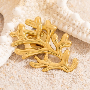 Broche corail dorée sur sable blanc avec étoile de mer pour une ambiance de vacances d'été