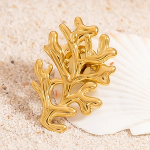 Broche en acier inoxydable doré en forme de corail sur coquillage blanc et sable